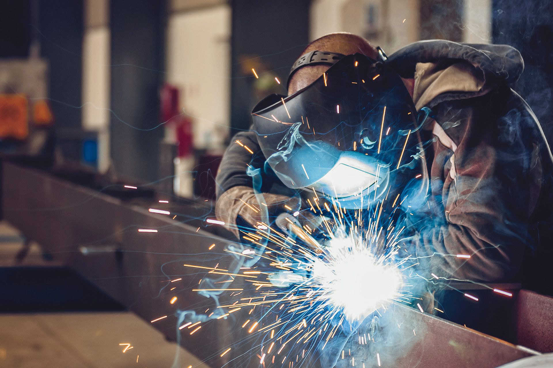 Welder at work on a steel beam, sparks flying