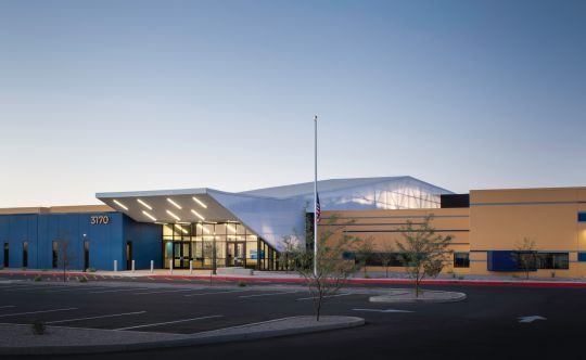 Low school building with a curved canopy at dusk