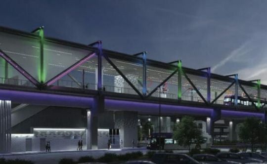 Steel bridge lit in coloured lights over a station at night