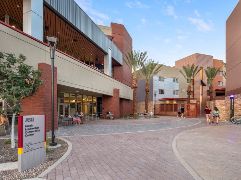 Paved courtyard between brick buildings and palm trees